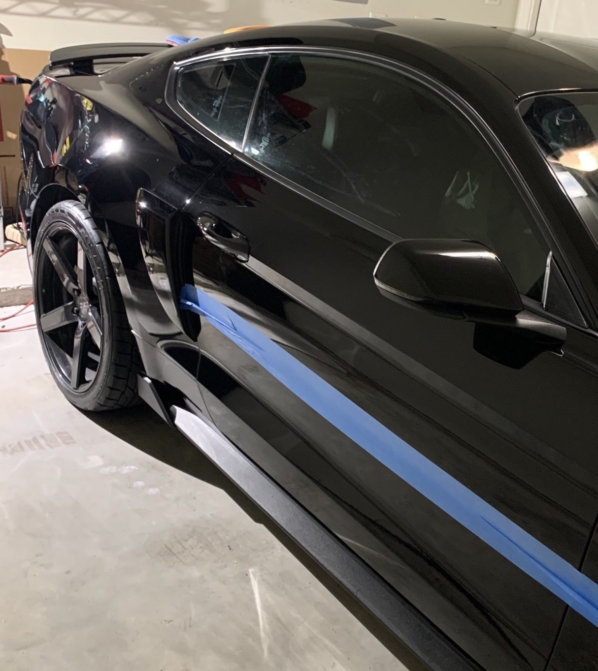 Black Mustang taped off for paint correction